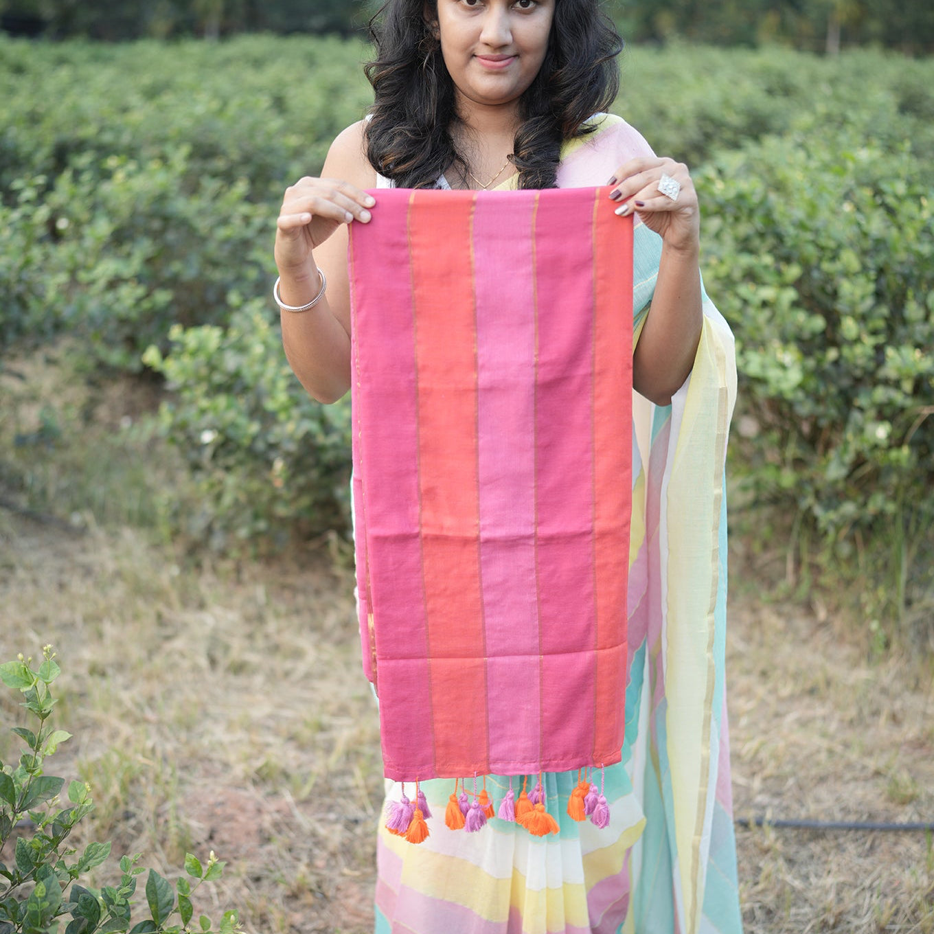Woman holding a colorful striped saree in an outdoor setting