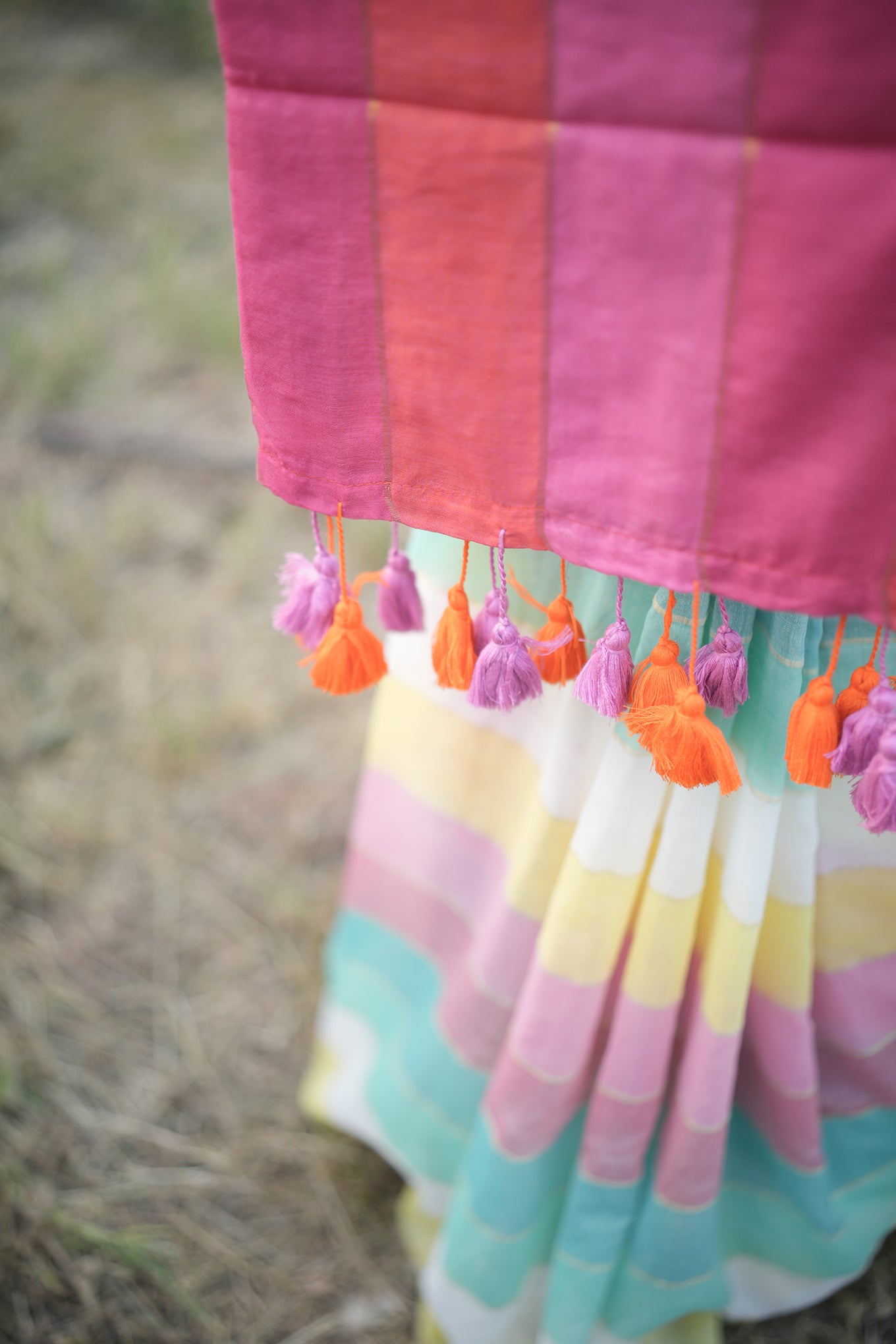 Close-up of a colorful dress with tassels on a blurred natural background